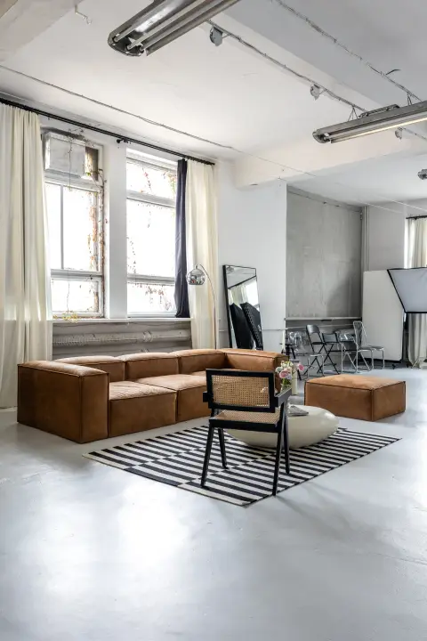 Studio fotograficzne SPOT, strefa lounge ze skórzaną sofą i czarno-białym dywanem